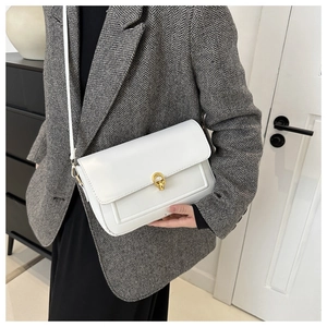 Sac bandoulière en cuir blanc avec boucle dorée porté sur un modèle en blazer gris
