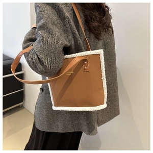 Detail of brown faux leather tote with white fleece trim and gold KNYISSA branding logo