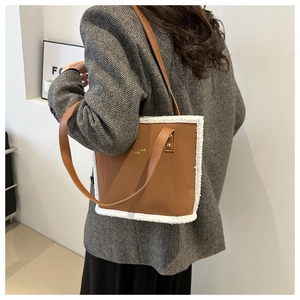 Close-up of brown tote bag featuring white faux fur trim and gold metal branding