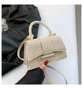 Close-up of beige woven texture and circular tube buckle on stylish crossbody handbag