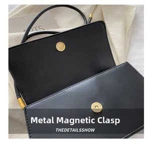 Detail einer hochwertigen schwarzen Lederhandtasche mit goldenem runden Magnetverschluss