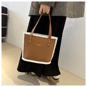 Close-up of the brown leather tote bag with white shearling trim and gold brand logo
