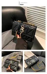Detail of black quilted crossbody bag with gold S-shaped logo and fringe chain strap