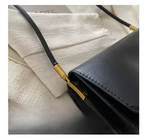 Nahaufnahme der schwarzen Ledertasche mit goldener Metallhardware und Schraubendesign