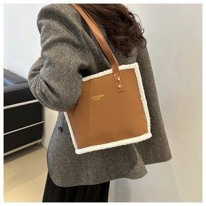 Detail of brown leather shoulder bag with white faux fur trim and gold logo lettering