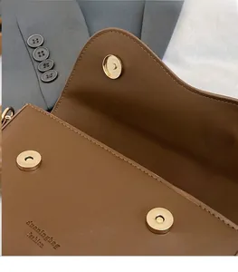 Détail d'un sac en cuir marron foncé avec fermoir magnétique et coutures précises