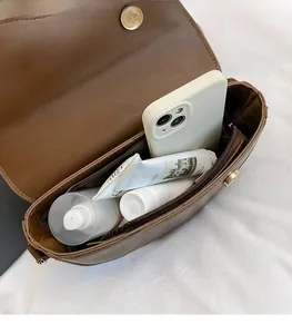 Vue détaillée de l'intérieur du sac besace en cuir marron et poche latérale zippée
