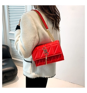 Detail of red quilted shoulder bag featuring gold S-shaped buckle and metal fringe accents