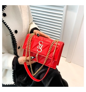 Close-up of red quilted shoulder bag with gold chain, S-logo buckle and decorative tassel