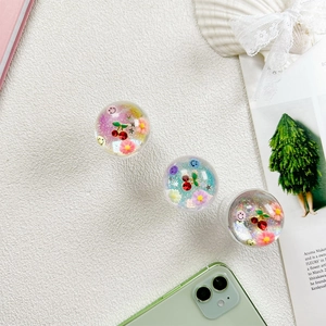 Gros plan de supports de téléphone à paillettes cerise et smiley avec fleurs