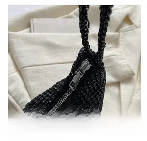 Detailed close-up showing the smooth silver metal zipper on a black rhinestone handbag