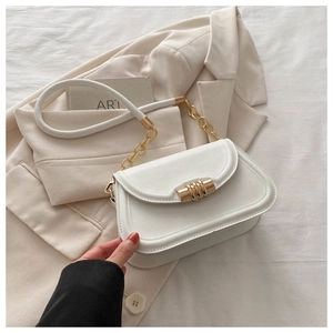 Detail of white chain shoulder bag with gold hardware on a stylish beige blazer