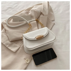 Close-up of minimalist saddle bag with gold metal buckle and leather strap on beige blazer