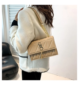 Detail of beige quilted shoulder bag with gold metal S logo and tassel chain strap