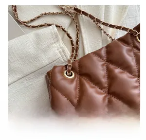 Macro shot of brown quilted bucket bag with gold eyelet detail and chain strap