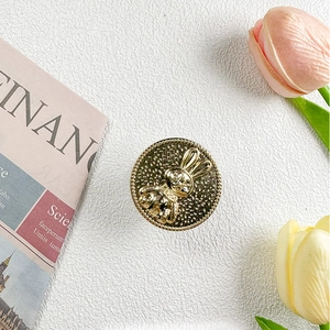 Close-up of golden rabbit emblem phone stand with tulip flowers and vintage newspaper decor
