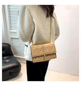 Detail of apricot quilted shoulder bag with gold chain and metal tassel on a model