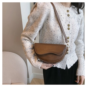Détail du sac besace en cuir PU marron avec rabat ondulé et logo gravé