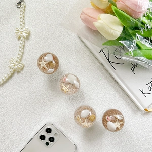 Detailed close-up of four telescopic phone grips featuring sea shells and starfish design