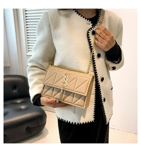 Detail of beige quilted shoulder bag with gold tassel hardware and metal chain strap