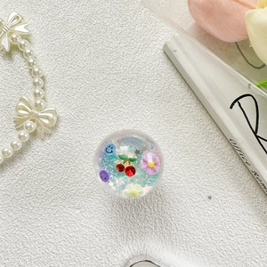 Détail macro du support téléphone cerise avec paillettes, fleurs et charms souriants