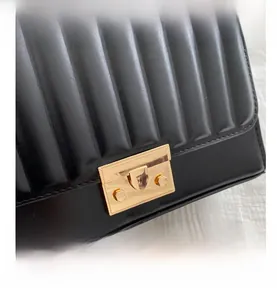 Detailed close-up of vertical quilted black leather with elegant gold rectangular clasp