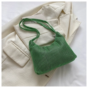 Detailed view of green rhinestone hobo bag with sparkling strap on a white blazer