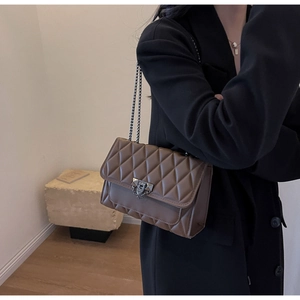 Dettaglio della borsa a spalla trapuntata marrone scuro con catena e chiusura vintage