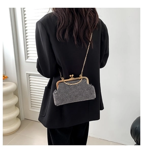 Detail of black rhinestone evening bag with gold clasp bag with gold chain strap on a black blazer