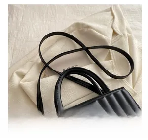 Detail of black pleated PU handbag featuring gold metal hardware and detachable strap