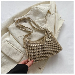 Detailed view of golden rhinestone hobo bag on a chic cream blazer for a party look
