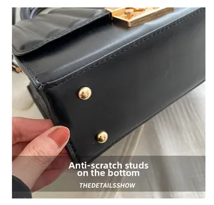 Detailed macro view of the black leather bag bottom featuring gold metal protective studs