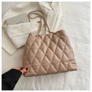 Close-up of beige quilted leather texture and woven gold chain strap on bucket bag