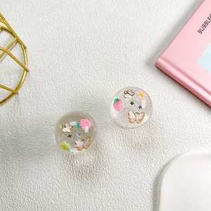 Close-up of glitter-filled resin ball grips with pink strawberry and butterfly charms