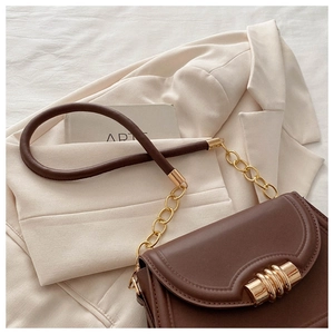 Close-up of brown leather saddle bag featuring a gold buckle and elegant curved stitching