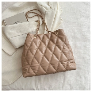 Detail of khaki quilted faux leather bucket bag with elegant golden chain strap and texture