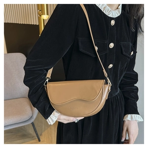Détail d'un sac besace marron en cuir avec bandoulière réglable et boucle en métal doré