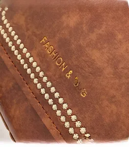 Detail of dark brown leather texture with gold lettering and vintage petal stitching