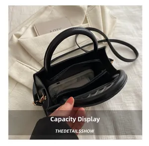 Top-down macro view of the three-compartment interior and zipper pocket in the black leather bag