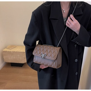 Dettaglio di una borsa a tracolla trapuntata marrone con catena dorata su un modello
