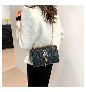 Detail of quilted shoulder bag with gold SS logo and fringe on a chain strap