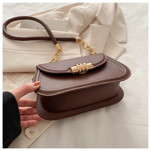 Close-up of dark brown faux leather bag featuring a gold spiral metal buckle and chain strap