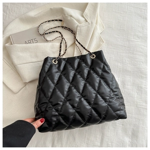 Close-up of black quilted bucket bag with chain strap and glossy leather finish