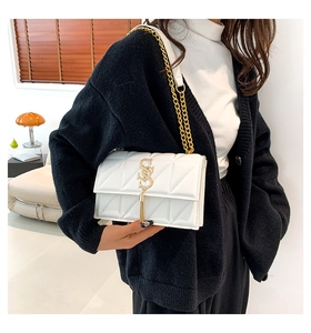 Close-up of white quilted handbag with golden S hardware and elegant chain strap details