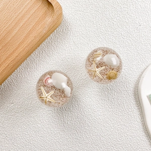 Close-up of ocean-themed phone grip with resin-encased shells, starfish, and fine sand