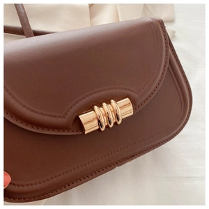 Close-up of the dark brown leather bag showing golden spiral buckle and fine stitching