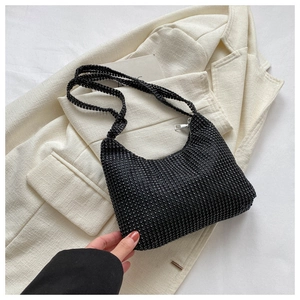 Close-up of black rhinestone hobo bag with sparkling crystals on a beige blazer