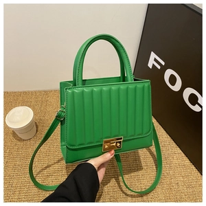 Detail of green quilted handbag featuring a golden rectangular clasp and leather texture