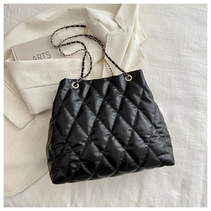 Detail of black quilted bucket bag with chain shoulder strap and elegant texture