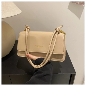 Detail der beigen Ledertasche mit goldenem Markenlogo und geknotetem Schultergurt